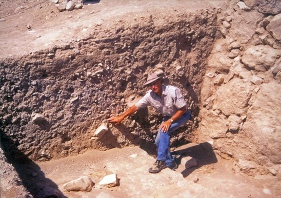 Arqueólogo apontando para tijolos desmoronados em Jericó